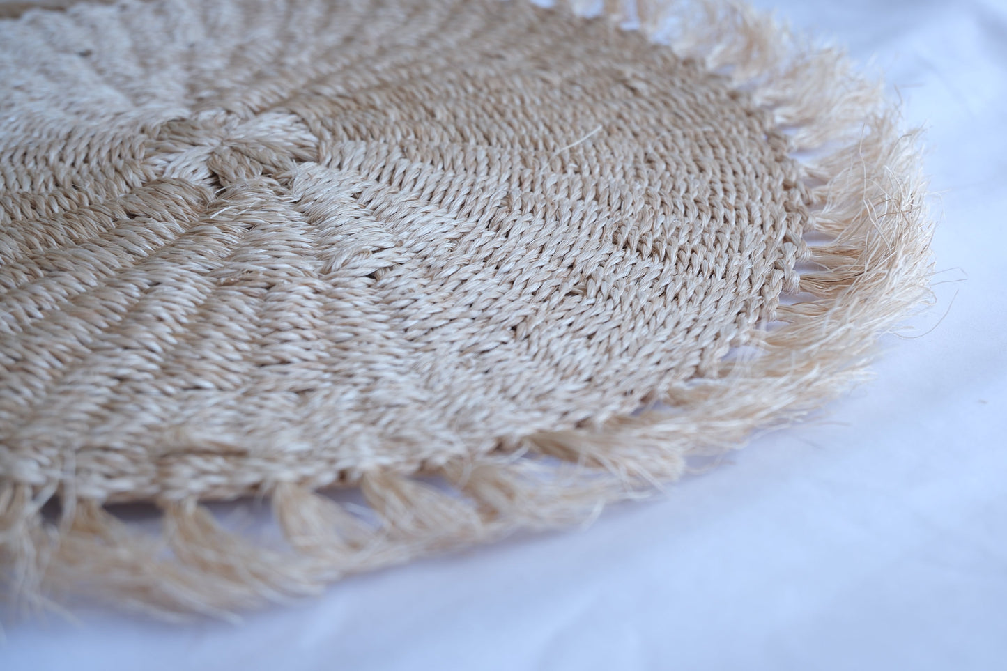 Close-up of a woven straw hat with fringes on a white background